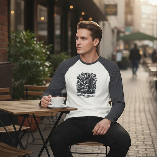 Man sitting outdoors with a cup of coffee, wearing a baseball shirt with a graphic design.