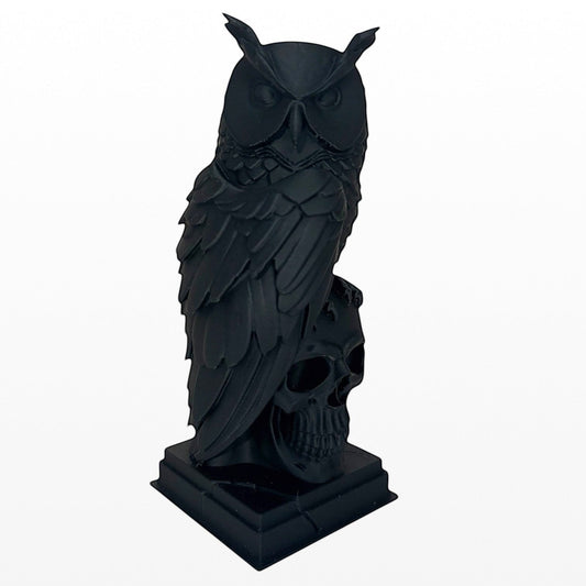 Illustrated Solutions Store black gothic owl figurine perched on a skull base, detailed feather design.