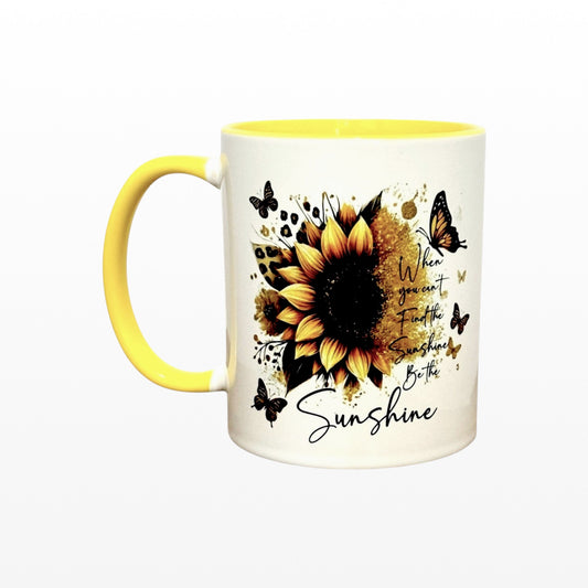 Illustrated Solutions Store white ceramic mug with yellow handle and interior, featuring a sunflower, butterflies, and the text "When you can't find the sunshine, be the sunshine."