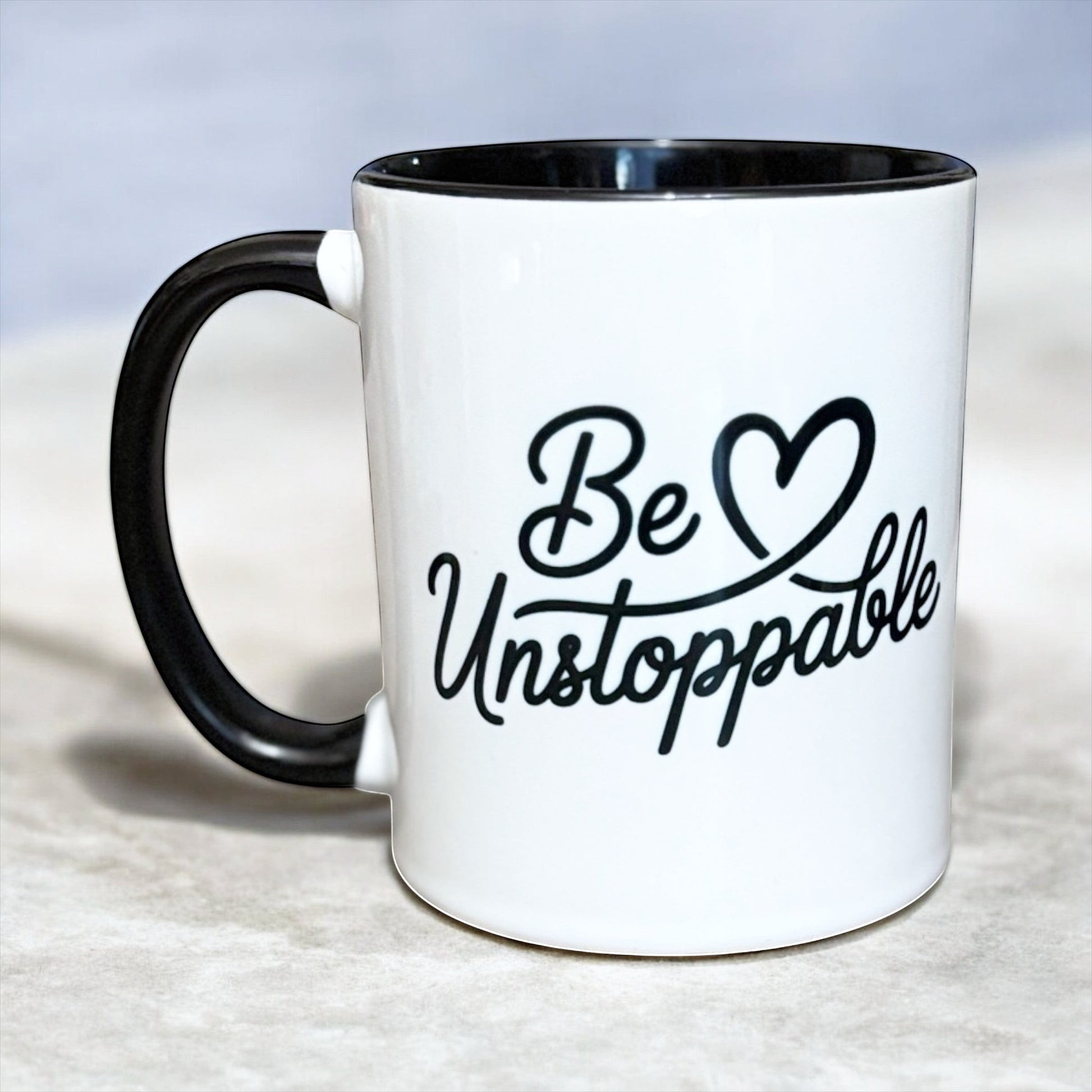 White ceramic mug with black interior and handle featuring Be Unstoppable motivational design, hand printed in the UK