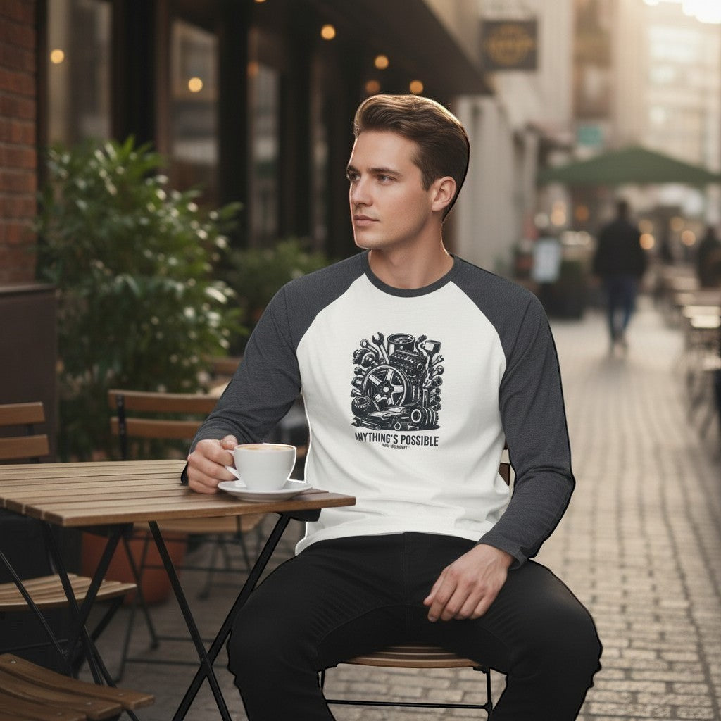 Man sitting outdoors with a cup of coffee, wearing a baseball shirt with a graphic design.