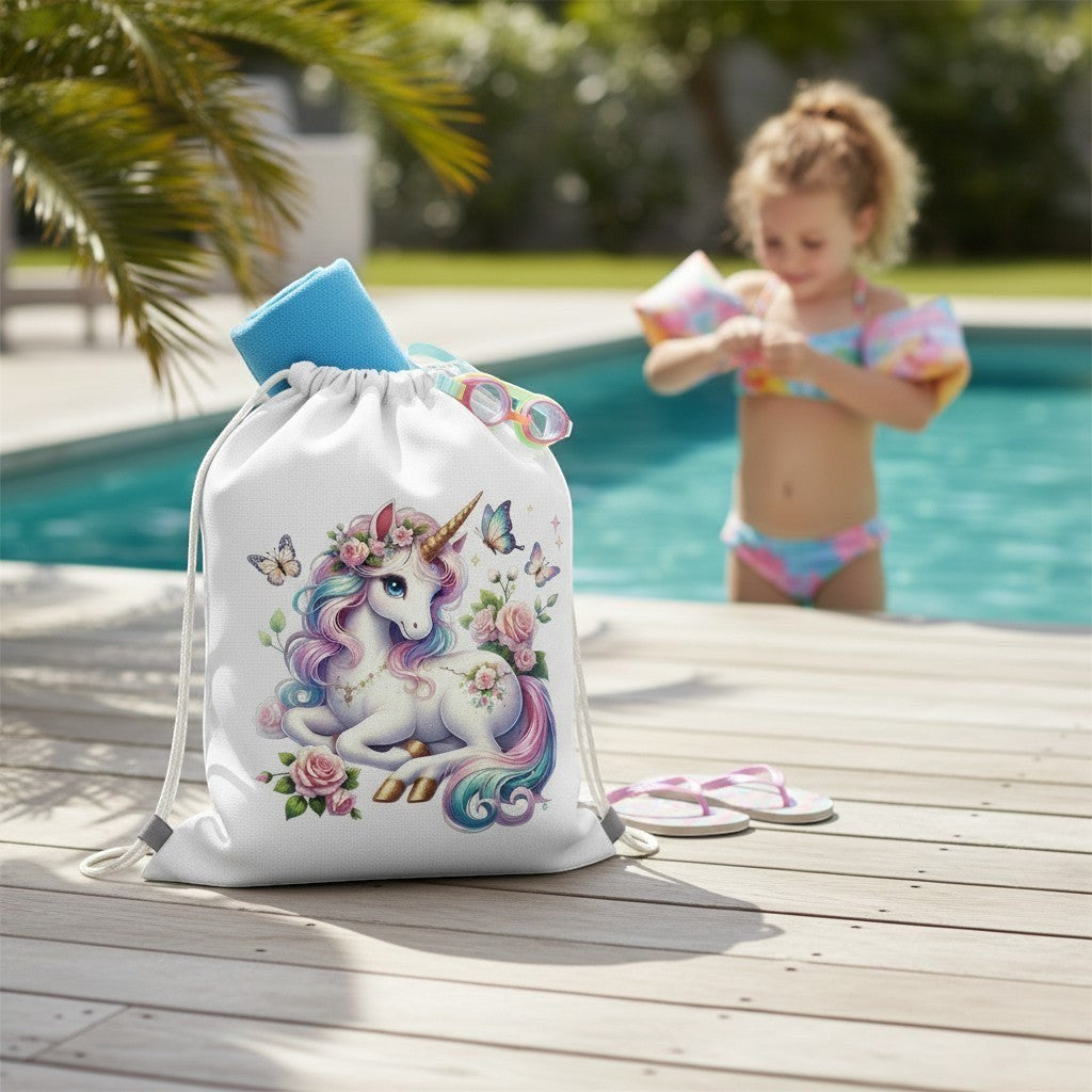 Drawstring bag with unicorn design on a wooden deck by a pool, with a child playing in the background.