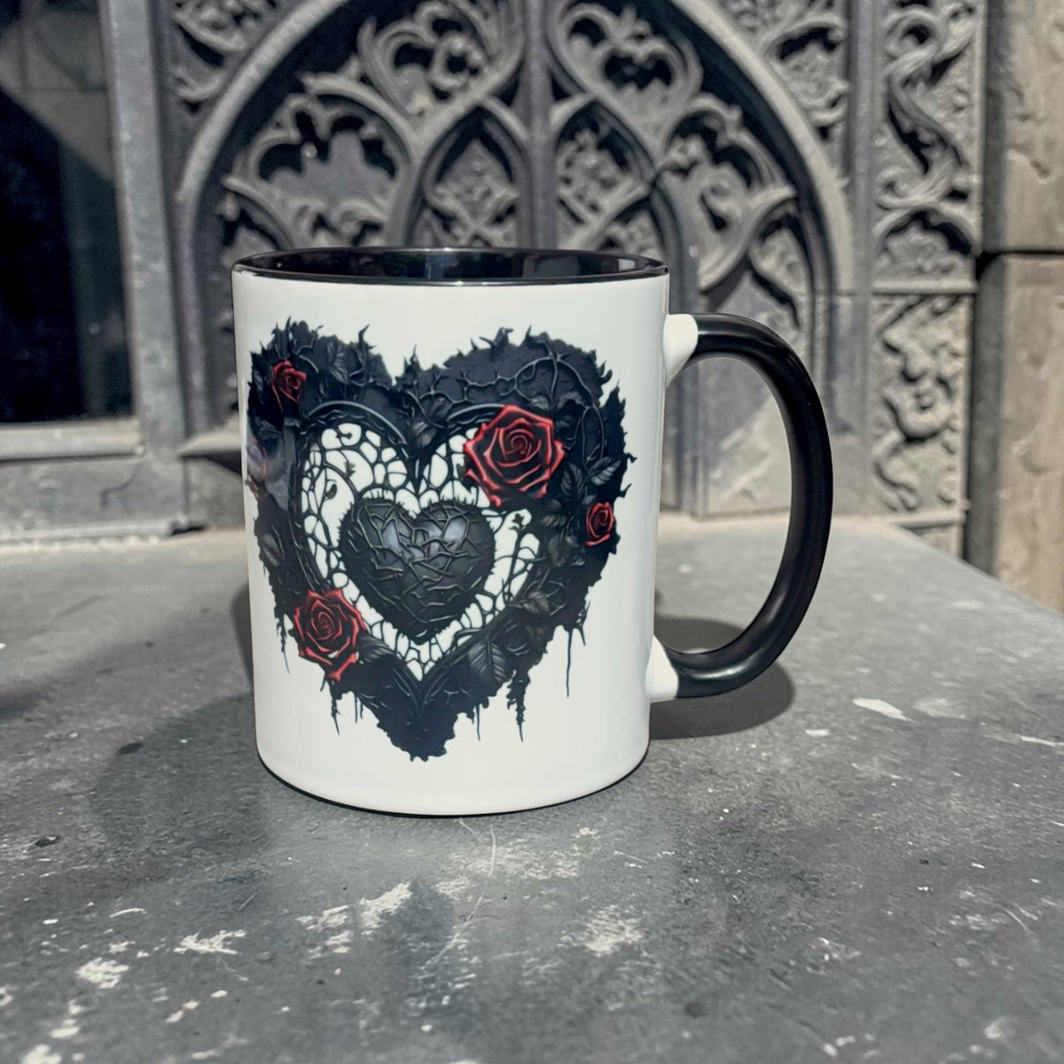 White mug with black heart and roses design on a textured surface