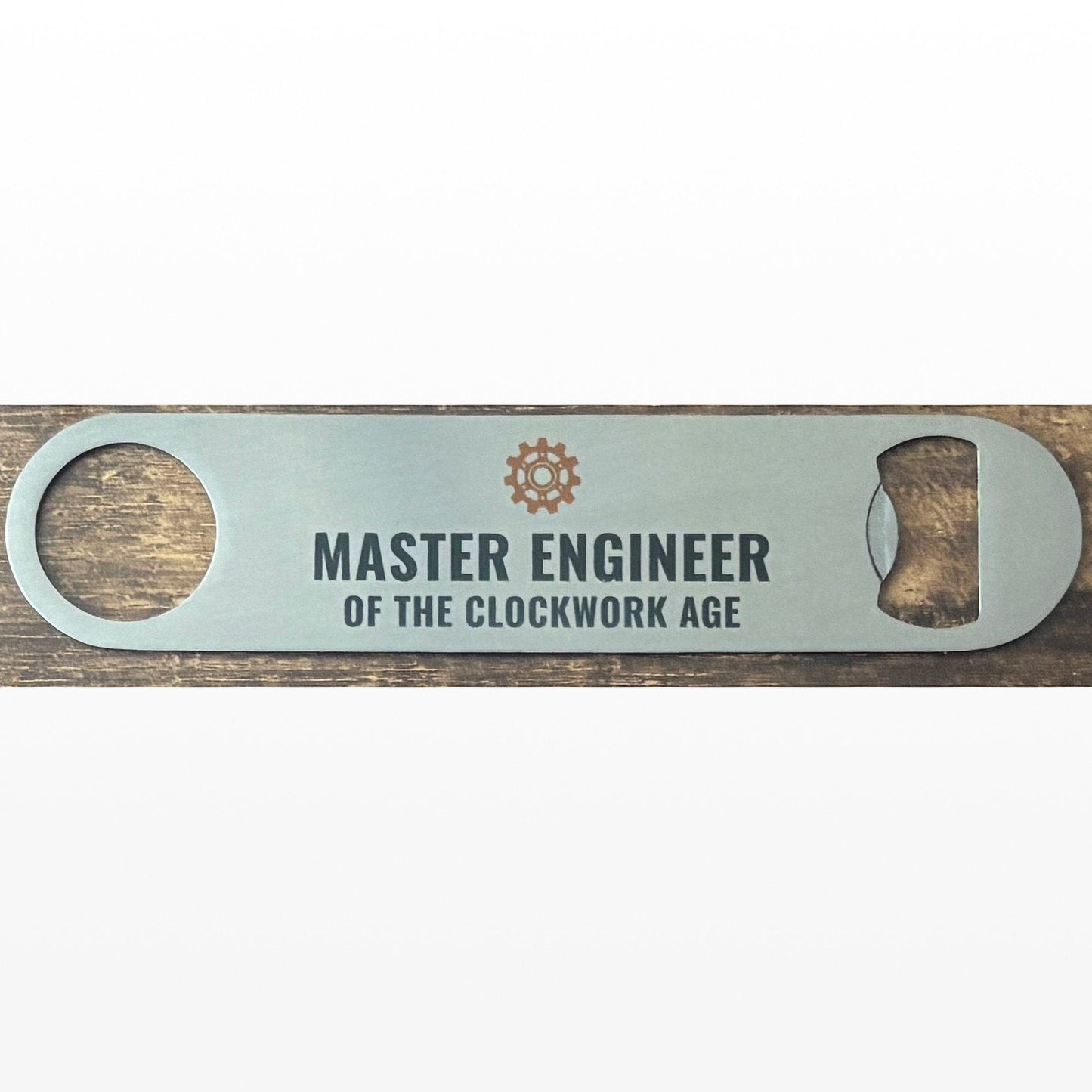 Stainless Steel Bar Blade with Steampunk Cog and Master Engineer Text in black. Bar blade on wooden table.