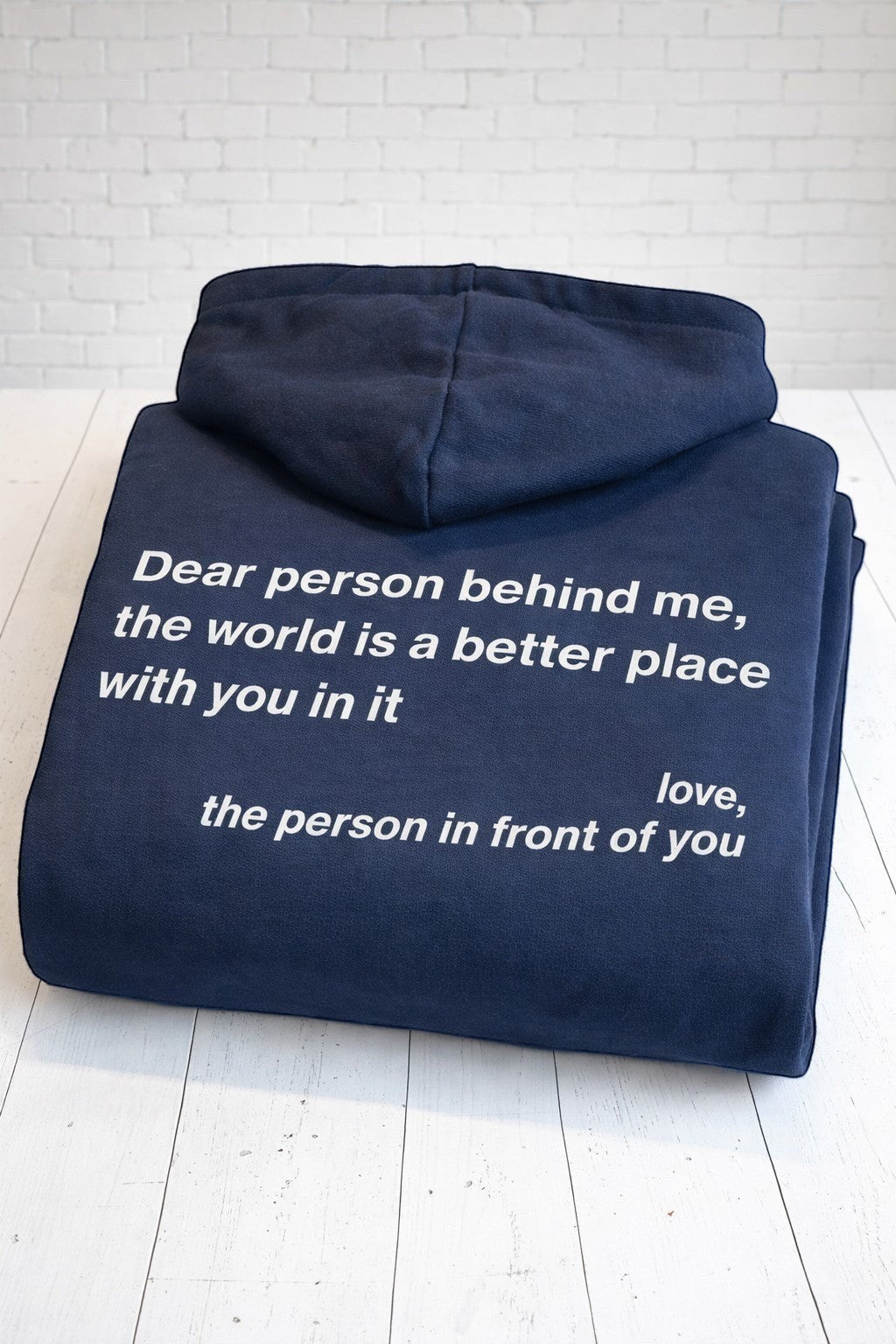 A folded up positive affirmation navy hoodie, showing the rear view. Hand-pressed in the UK.
