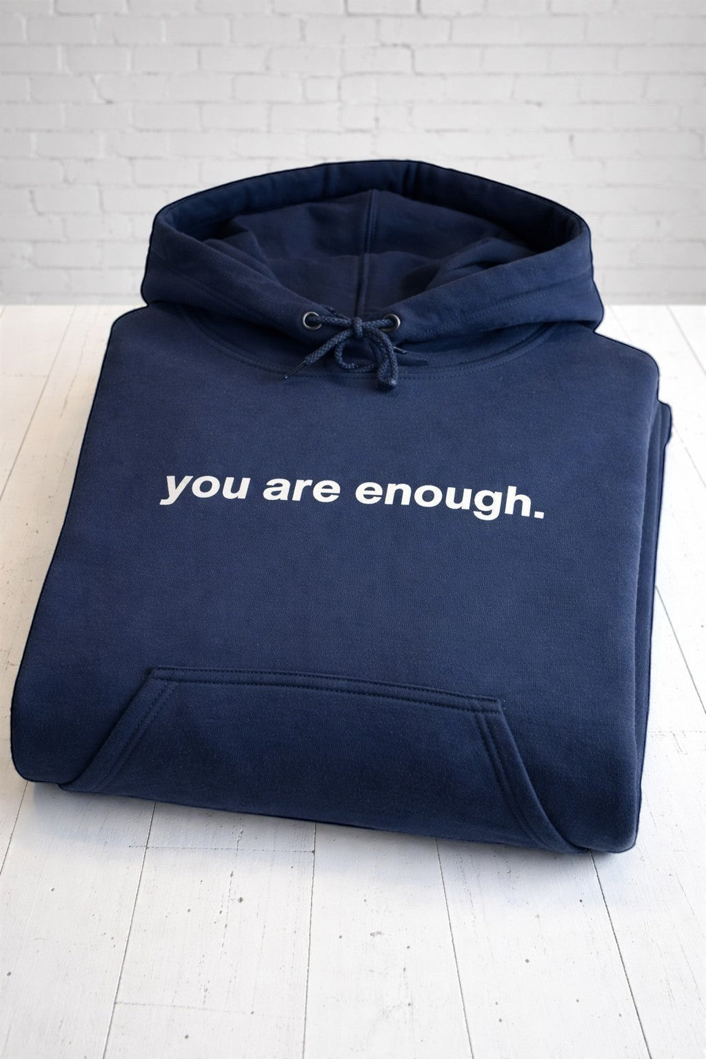 You are enough navy hoodie, folded, front view,. Hand-pressed with care in the UK