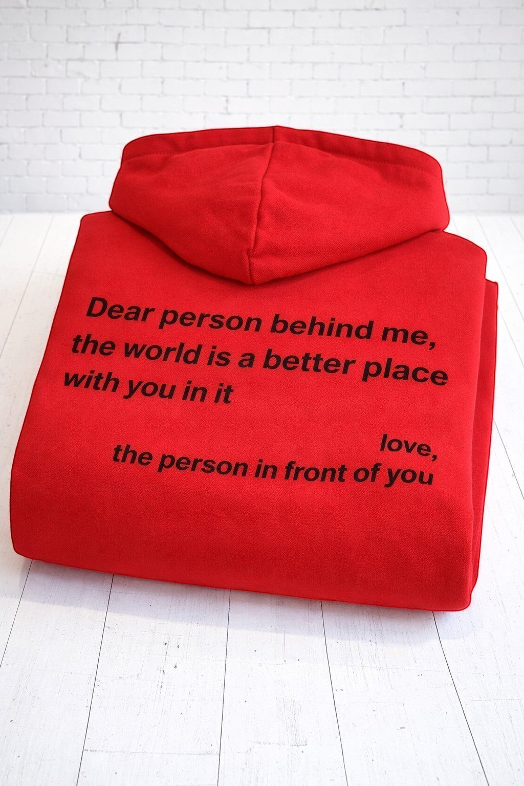 A folded up positive affirmation red hoodie, showing the rear view. Hand-pressed in the UK.