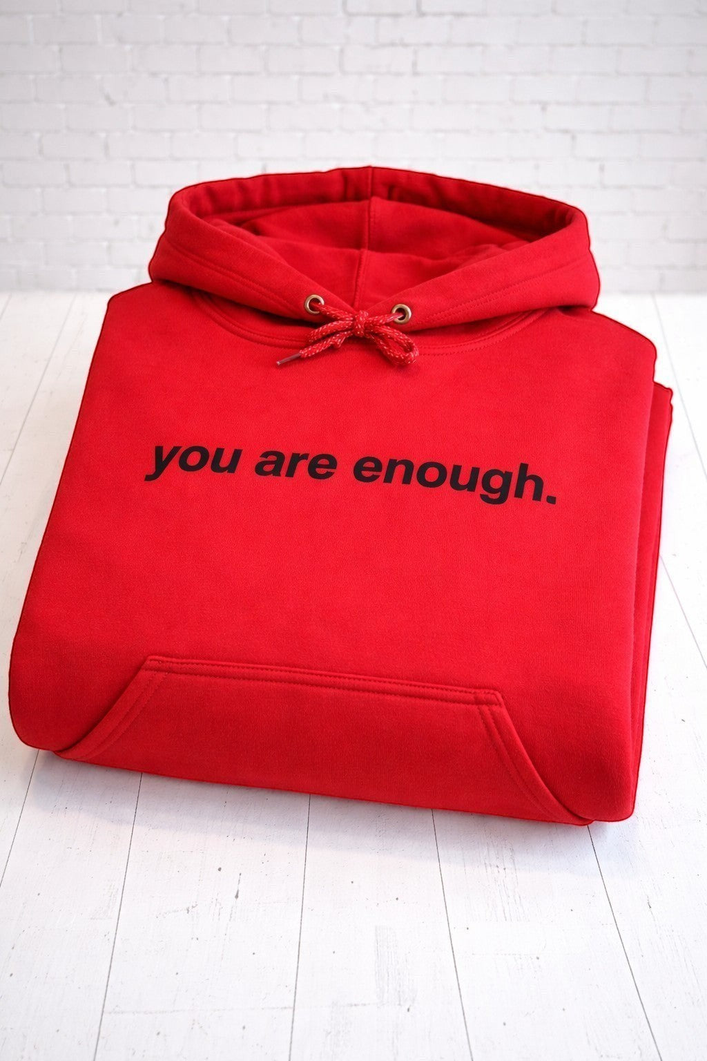 You are enough red hoodie, folded front view,. Hand-pressed with care in the UK