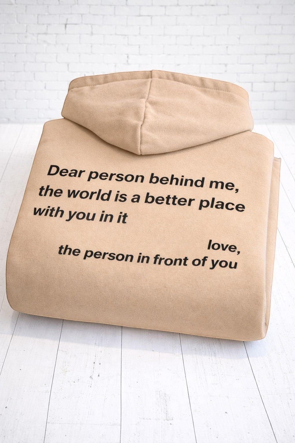 A folded up positive affirmation sand hoodie, showing the rear view. Hand-pressed in the UK.