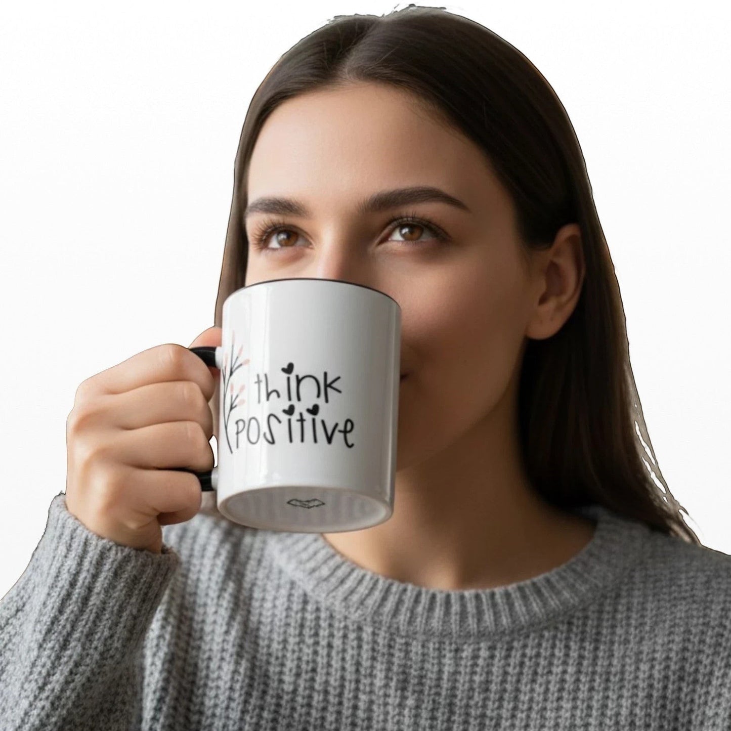 White ceramic mug with black handle and rim, featuring "think POSITIVE" text and floral design. Woman drinking from mug.