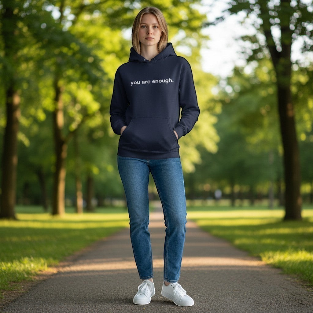 Person in a park, wearing a hoodie with white 'you are enough' text on the front of hoodie.
