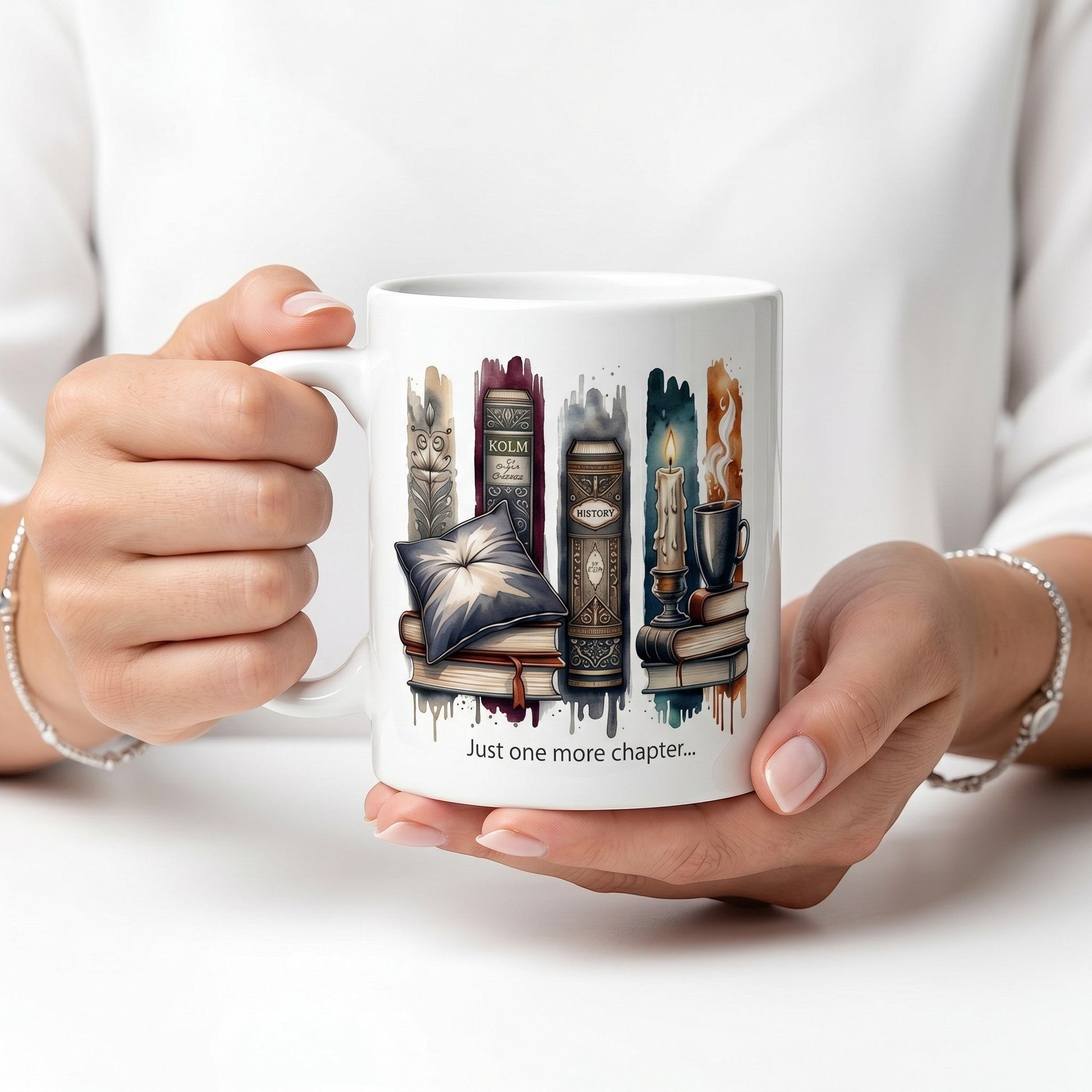 Lifestyle close-up of a perfect book lover gift of a ceramic mug featuring book-themed artwork and the text Just one more chapter held in hands