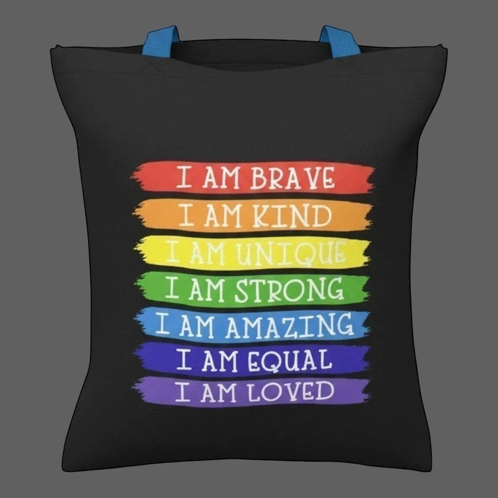 Illustrated Solutions Store black tote bag with rainbow stripes and affirmations like "I Am Brave" and "I Am Loved".