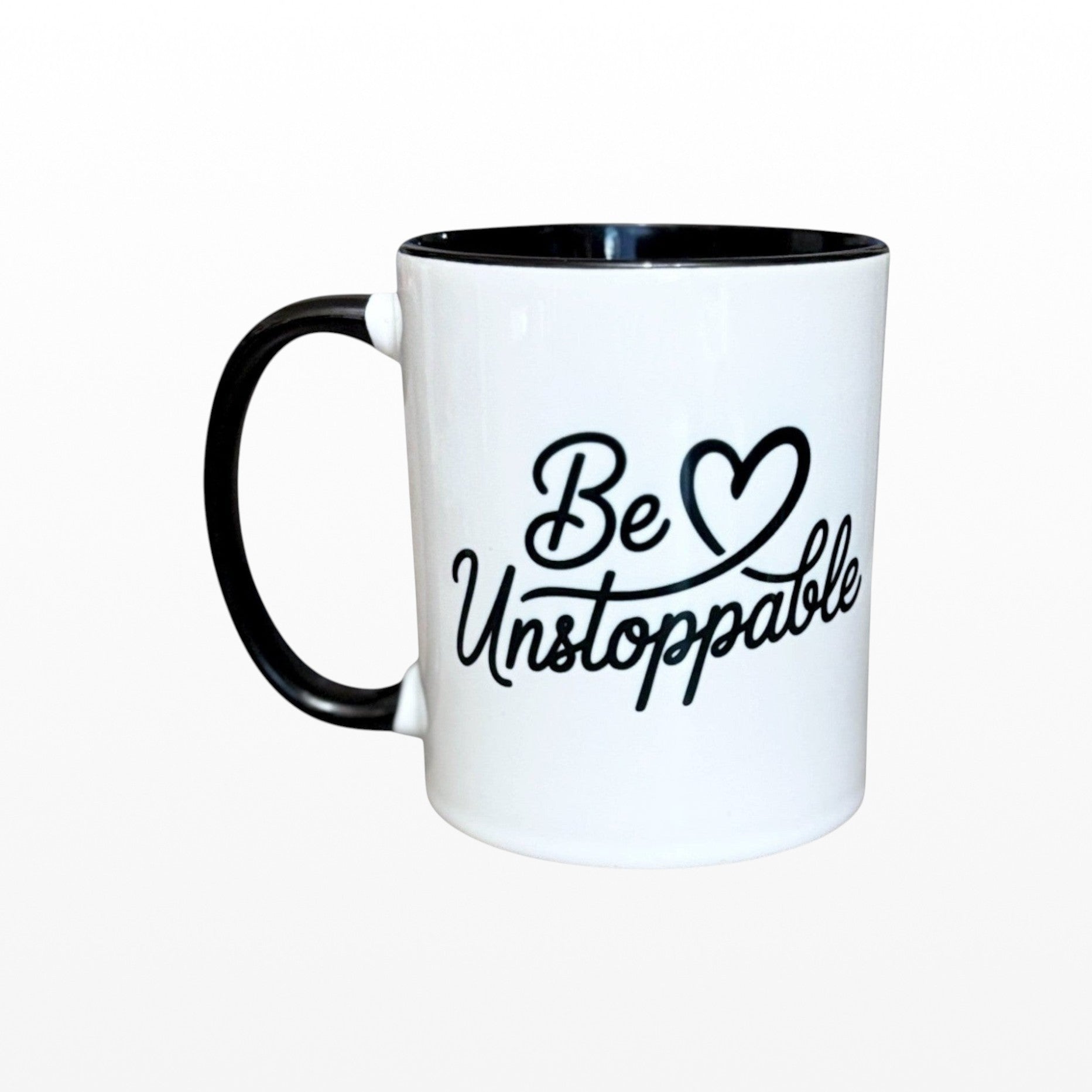 Illustrated Solutions Store white ceramic mug with black handle and interior, featuring the motivational phrase "Be Unstoppable" in black script.