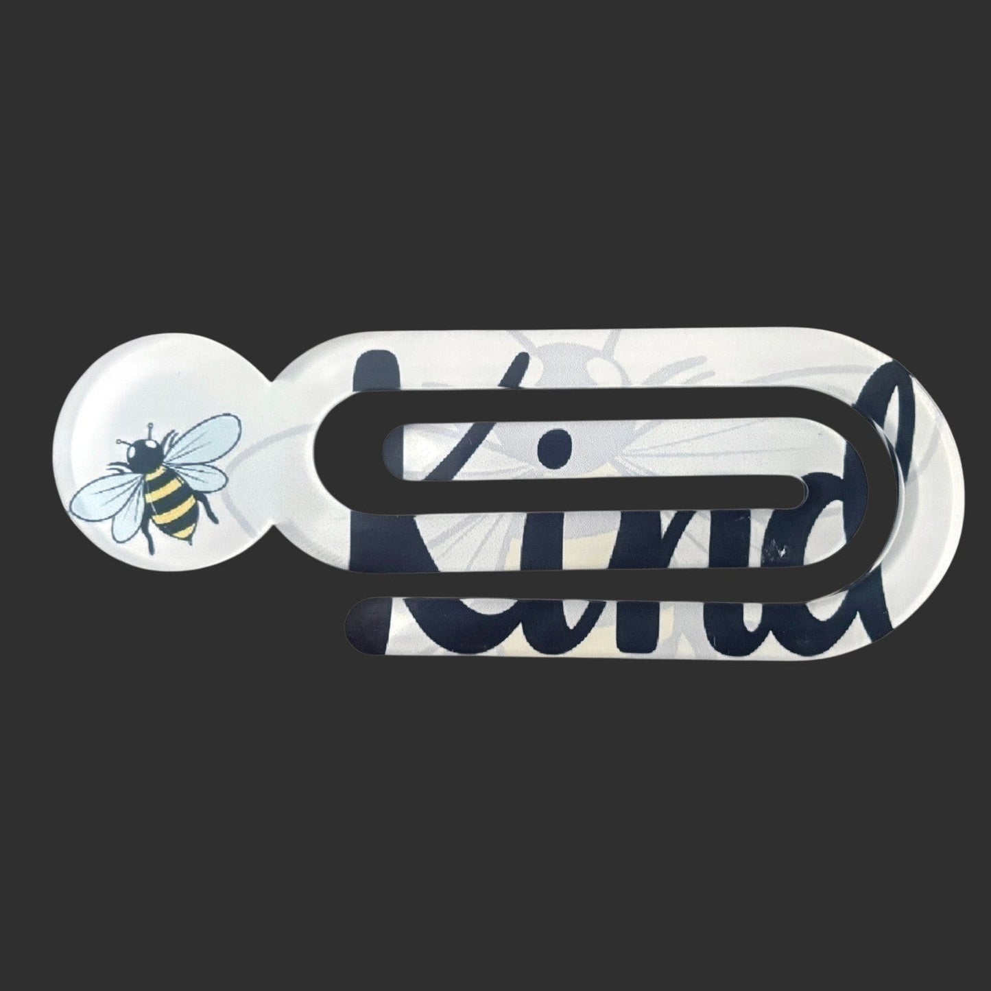 Illustrated Solutions Store acrylic book clip with a bumblebee design and Bee Kind text on a white background.