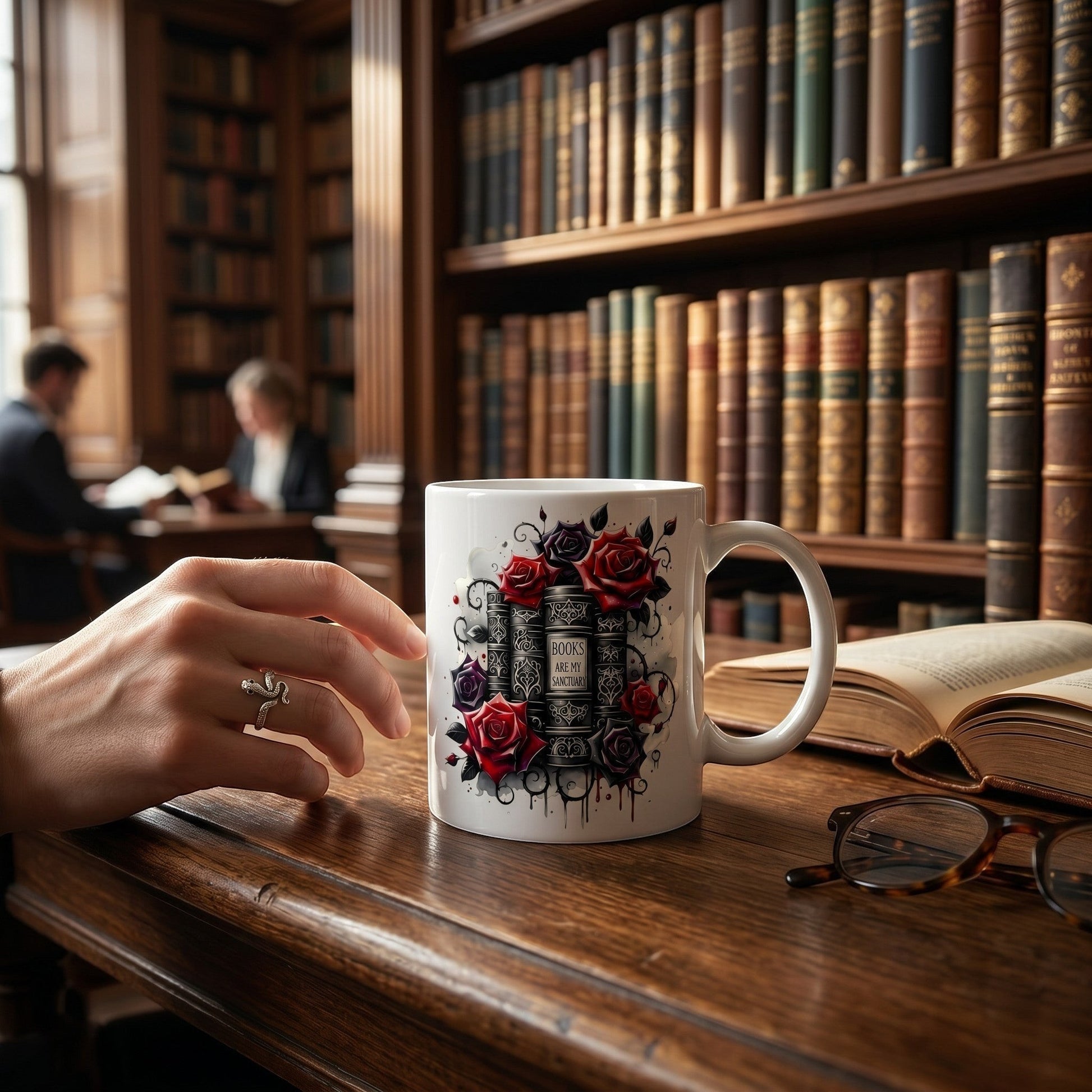 Illustrated Solutions Store ceramic mug featuring book stack and red rose artwork on a library desk