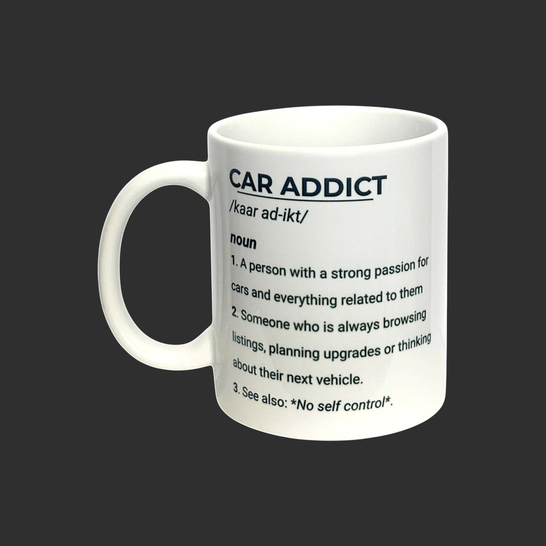 Illustrated Solutions Store white ceramic mug with black text defining 'Car Addict' and its pronunciation.