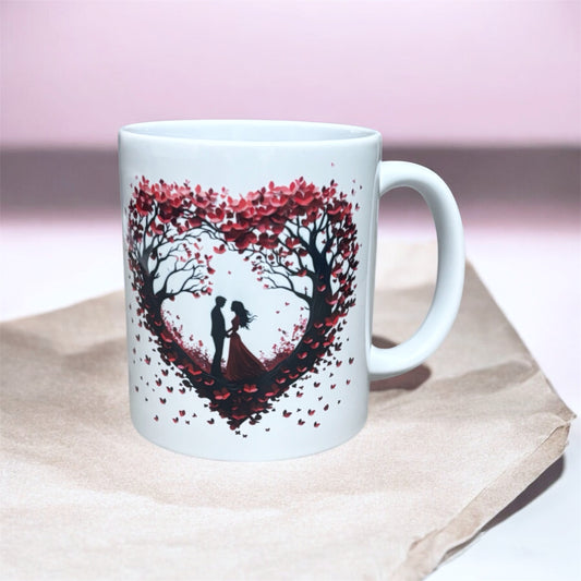 Illustrated Solutions Store couple heart mug with a silhouette of a couple under a heart-shaped tree with red leaves.