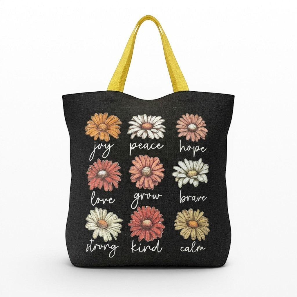Illustrated Solutions Store black tote bag with yellow handles, featuring a grid of daisies with positive affirmations like joy, peace, hope, love, grow, brave, strong, kind, and calm.