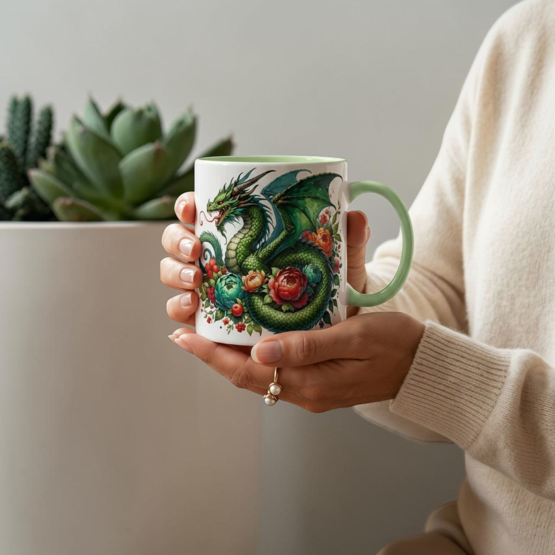 Illustrated Solutions Store 11oz ceramic mug featuring a green dragon and floral design on a light green handled mug held in hands