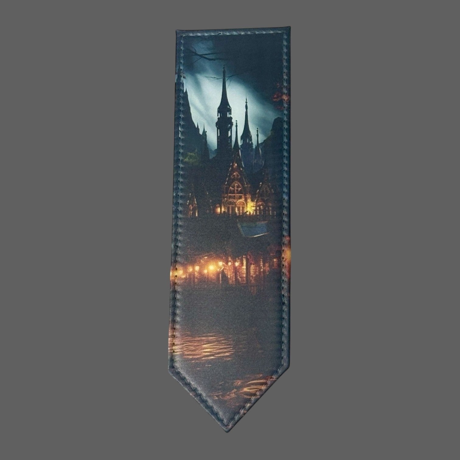 Illustrated Solutions Store leather bookmark featuring a dark gothic castle at night with glowing windows and reflections on water.