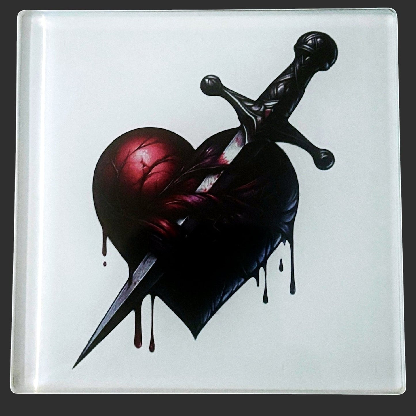 Illustrated Solutions Store gothic heart dagger glass coaster. Features a dark, dripping heart pierced by a dagger. Close-up view.