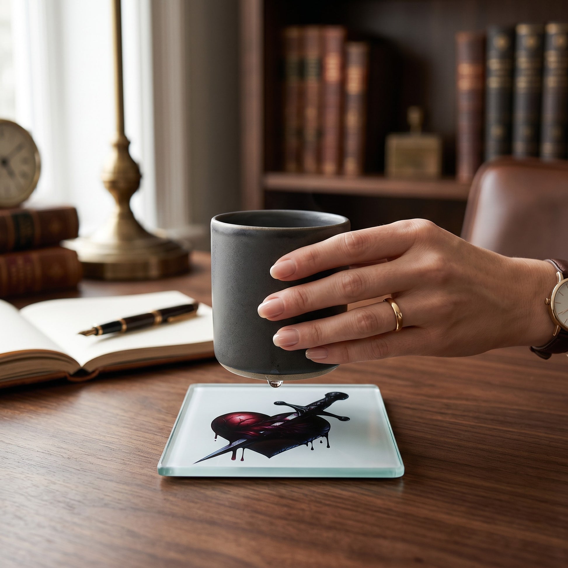 Illustrated Solutions Store square glass coaster featuring a gothic heart pierced by a dagger on a wooden desk.