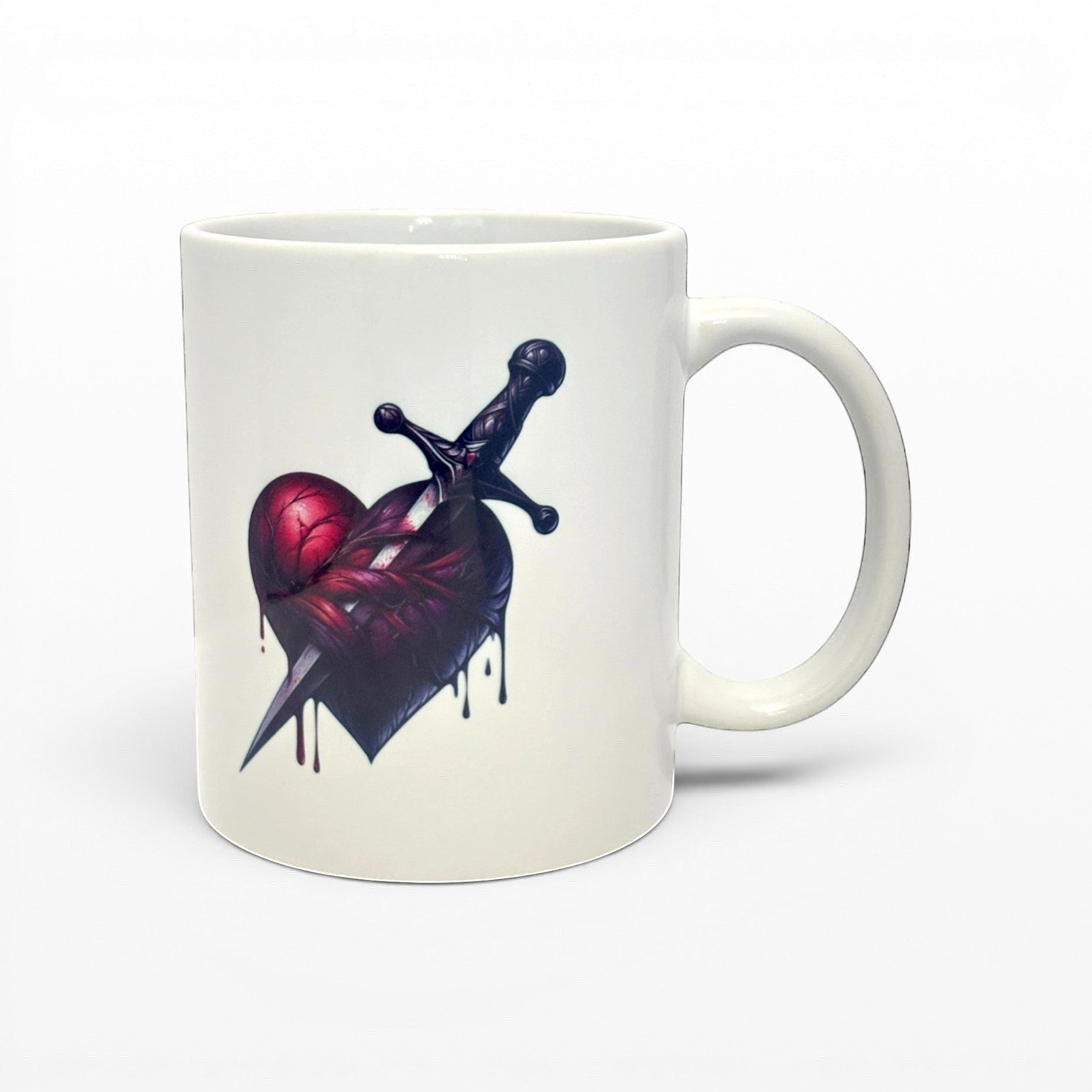 Illustrated Solutions Store white ceramic mug with a dark romantic Heart Dagger design, featuring a bleeding heart pierced by a dagger.