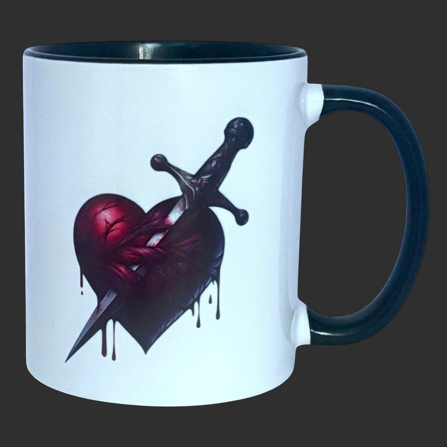 Illustrated Solutions Store white ceramic mug with black handle and rim, featuring a dark gothic heart pierced by a dagger.