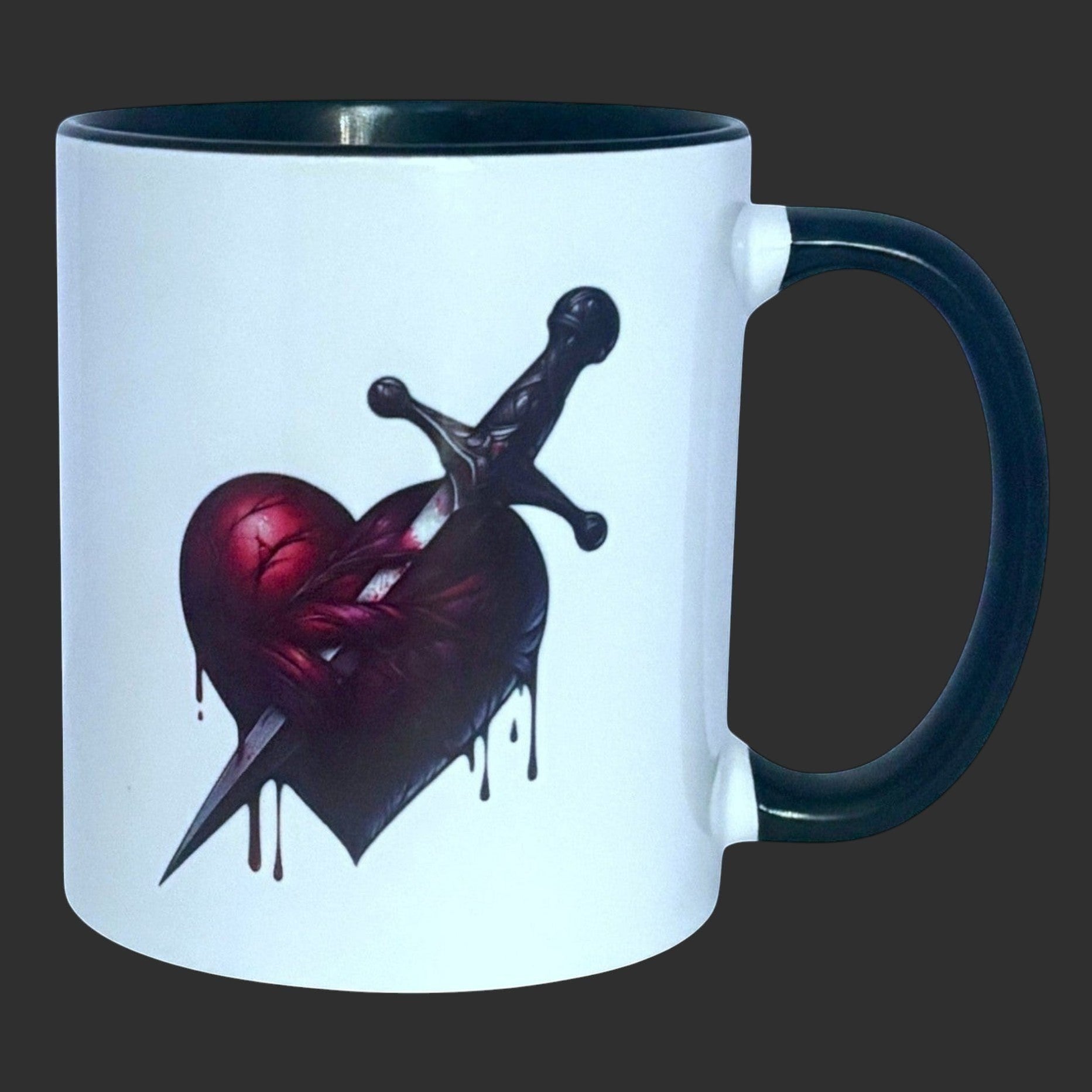 Illustrated Solutions Store white ceramic mug with black handle and rim, featuring a dark gothic heart pierced by a dagger.