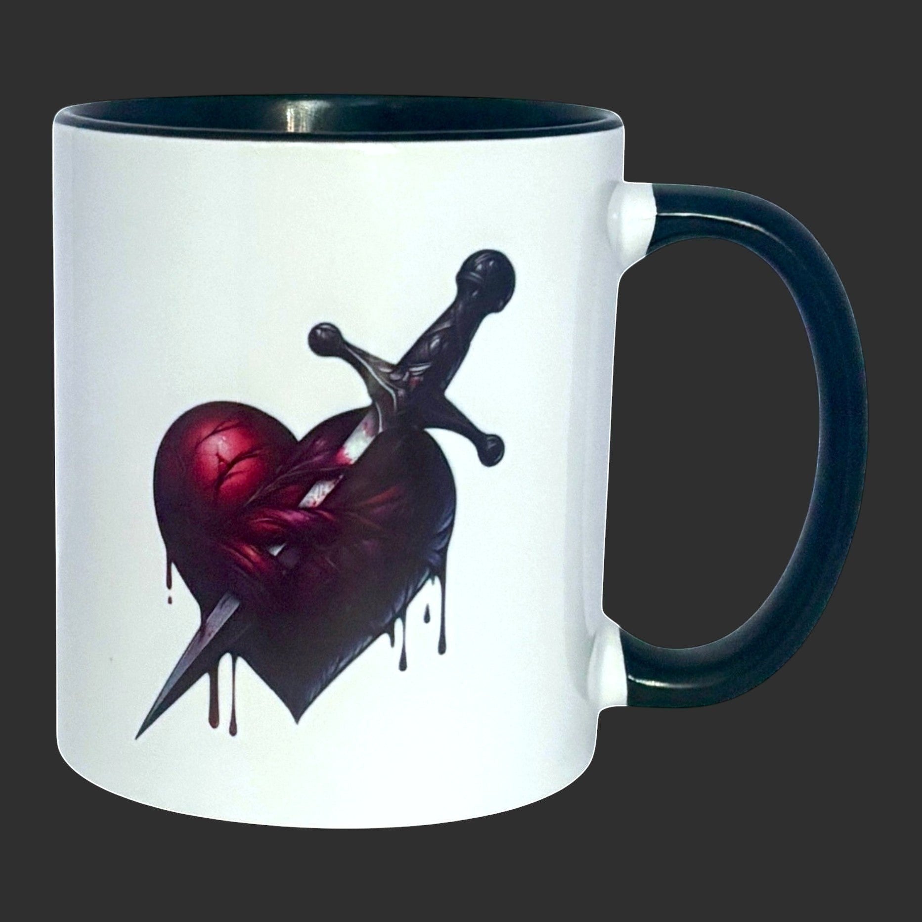 Illustrated Solutions Store white ceramic mug with black handle and rim, featuring a dark gothic heart pierced by a dagger.