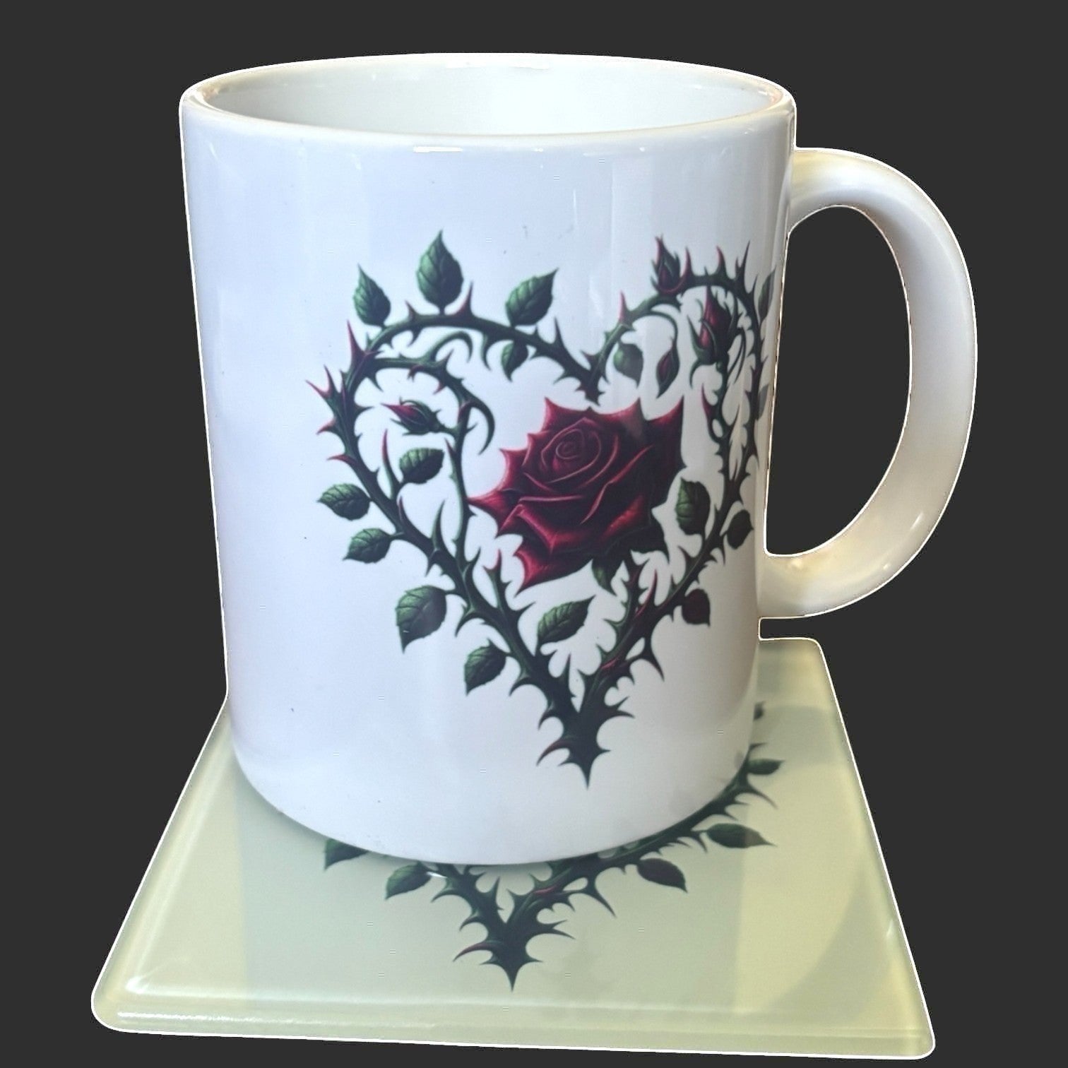 Illustrated Solutions Store gothic thorn rose heart glass square coaster with a dark red rose and thorny vines. Matching mug placed on the coaster.