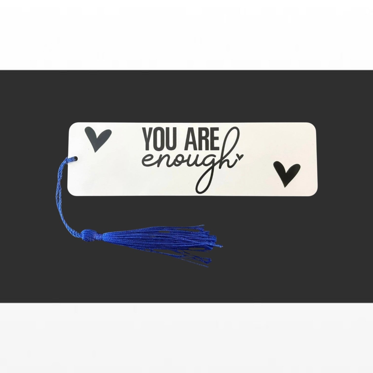 Illustrated Solutions Store metal bookmark with You Are Enough text and black hearts, featuring a blue tassel.