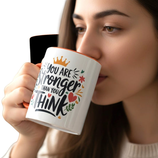 Illustrated Solutions Store white ceramic mug with orange handle and interior, featuring the quote "You are stronger than you think" with floral and crown graphics.