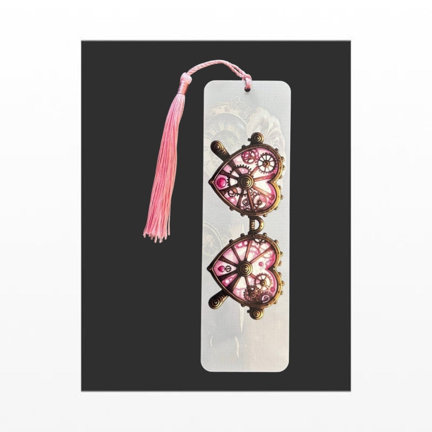 Illustrated Solutions Store metal bookmark featuring pink steampunk heart-shaped glasses with a matching pink tassel. Vertical view