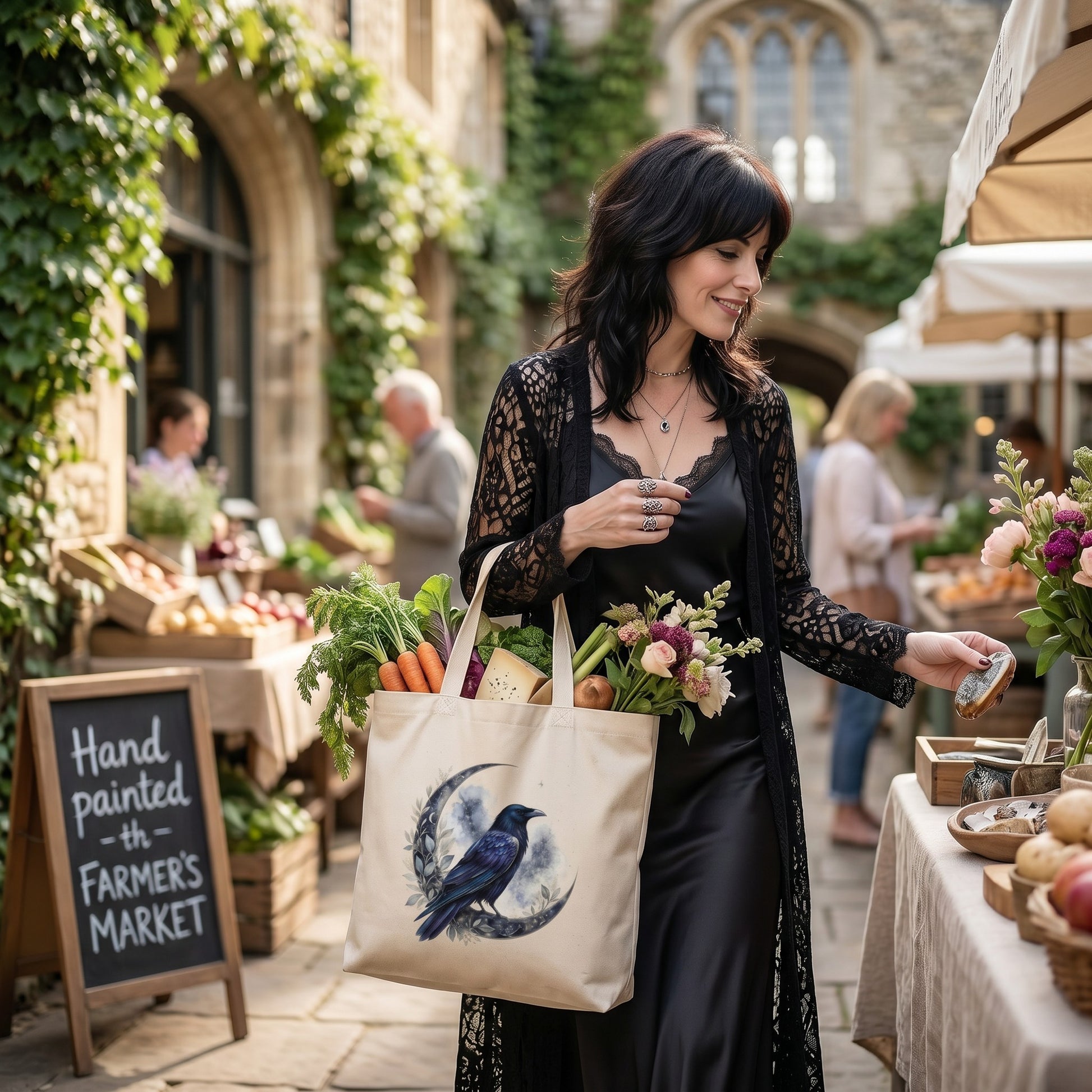 Illustrated Solutions Store canvas tote bag with raven and crescent moon print, carried by a woman at a market.