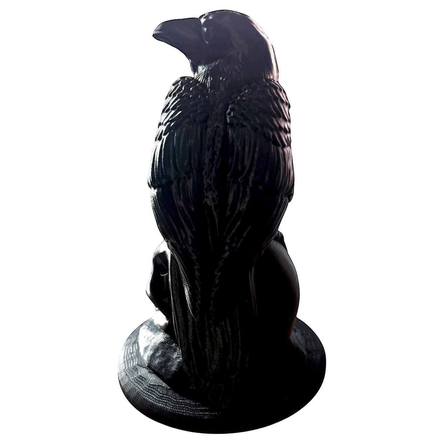 Illustrated Solutions Store matte black raven figurine perched on a skull base, gothic décor.
