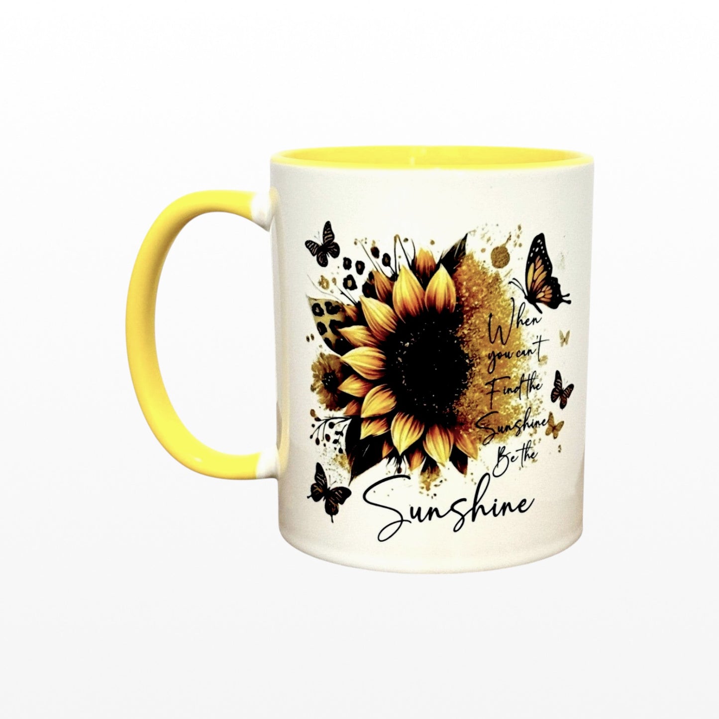 Illustrated Solutions Store white ceramic mug with yellow handle and interior, featuring a sunflower, butterflies, and the text "When you can't find the sunshine, be the sunshine."