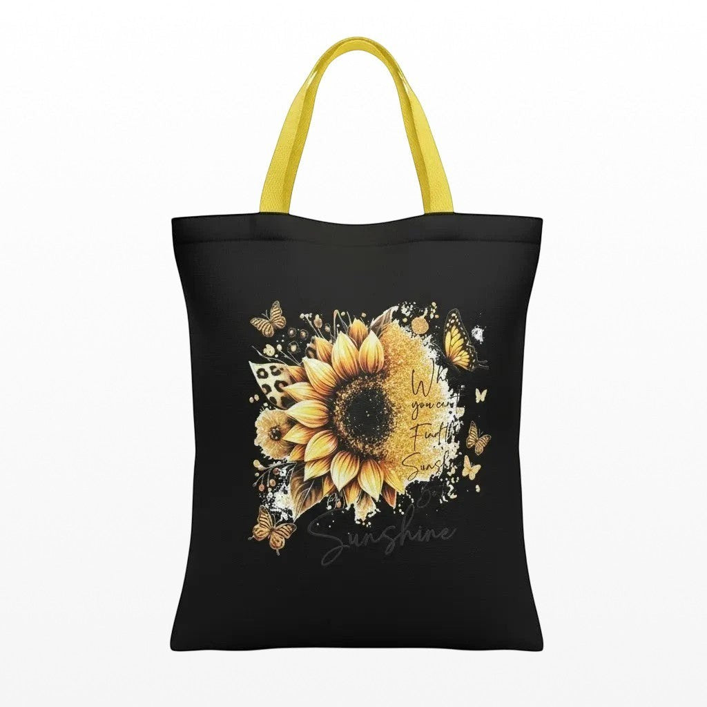 Illustrated Solutions Store black tote bag with yellow handles, featuring a sunflower design with butterflies and the text "When you can't find the sunshine, be the sunshine."