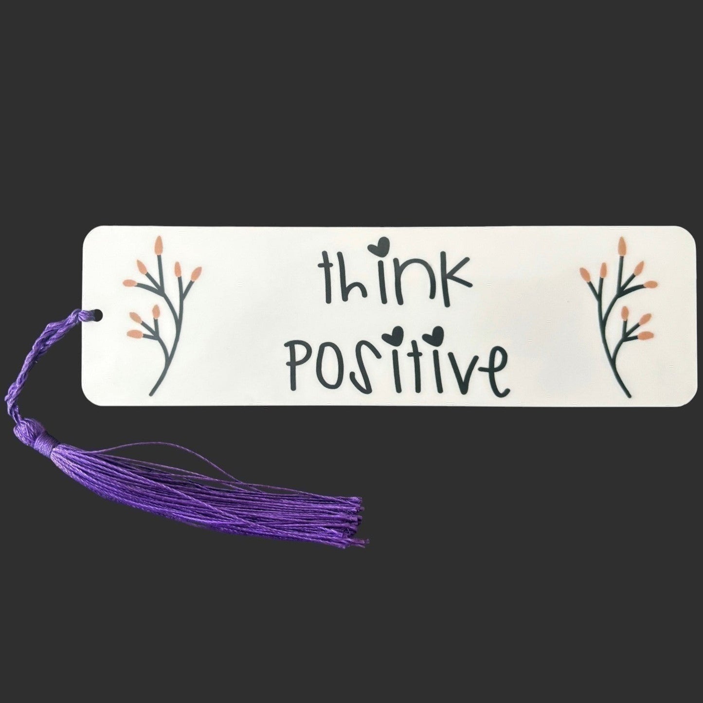 Illustrated Solutions Store aluminium bookmark with Think Positive text, floral accents, and a purple tassel. Large view dark background