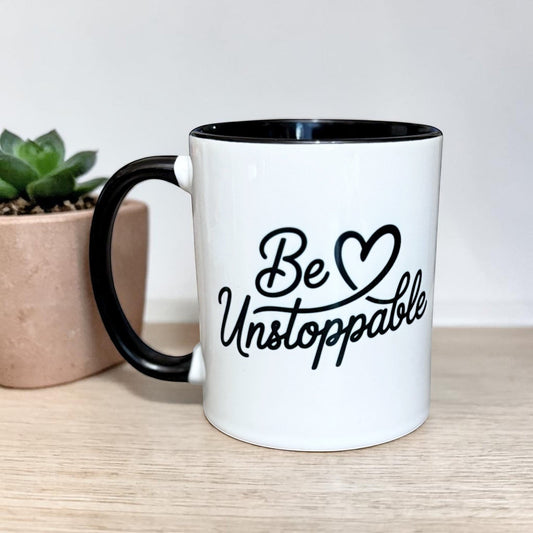 Illustrated Solutions Store white ceramic mug with black handle and rim, featuring the text "Be Unstoppable" in black script.