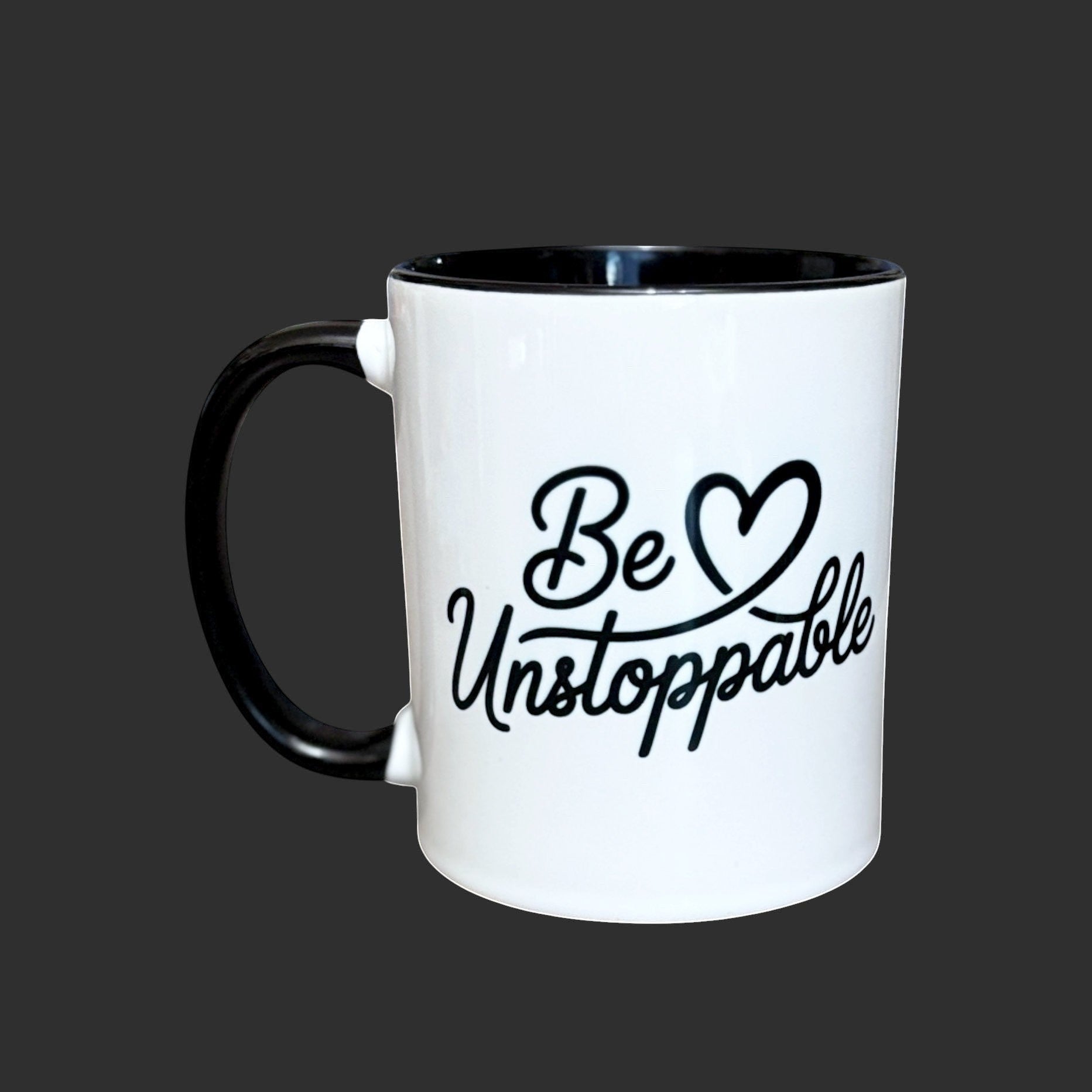 Illustrated Solutions Store white ceramic mug with black handle and rim, featuring the text "Be Unstoppable" in black script.