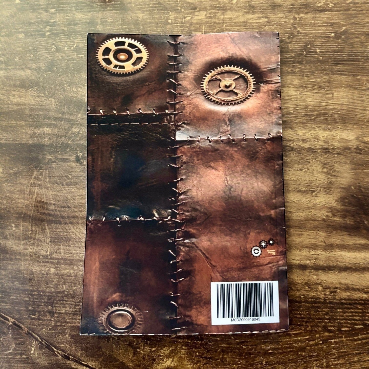 Illustrated Solutions Store steampunk journal with vintage leather-look cover, stitched seams, and brass gear details.