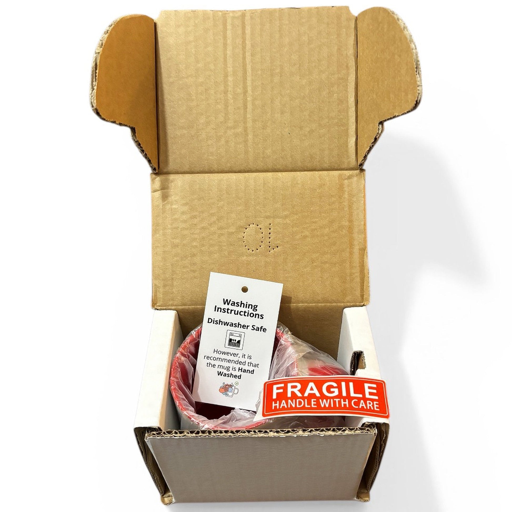 An open cardboard protective mug box containing a packaged red-handled mug with a white instruction card and a red-orange FRAGILE sticker, photographed on a white background.