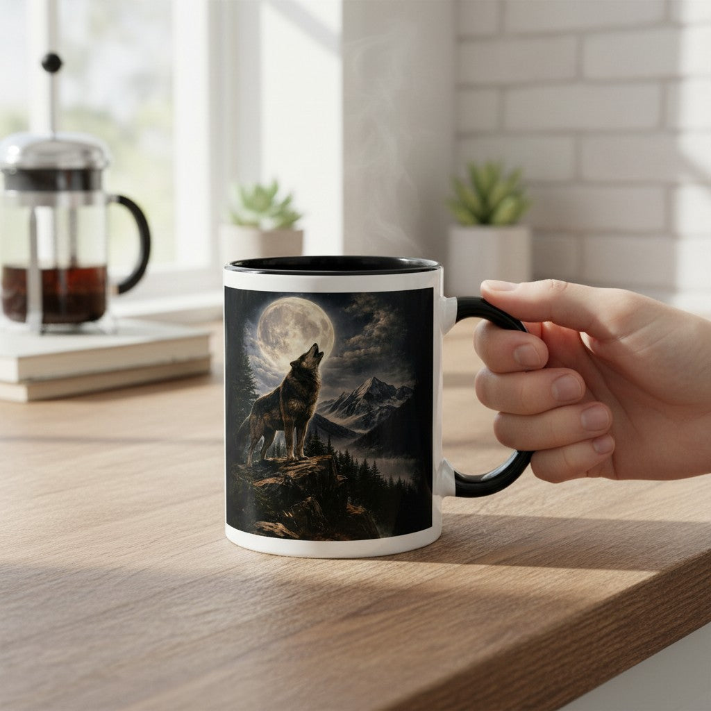 A hand holds a white ceramic mug with a black handle and rim, featuring a printed graphic of a howling wolf under a full moon in a mountain landscape. The mug sits on a wooden table in a bright kitchen setting with a French press and small plants in the background.
