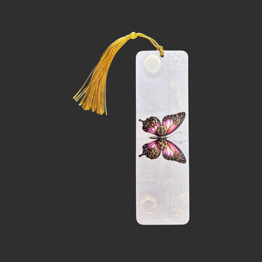 Vertical view of an aluminium bookmark featuring an original pink steampunk butterfly illustration with bronze clockwork detailing and a gold tassel.