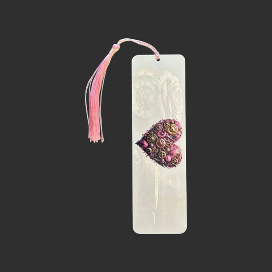 Vertical view of an aluminium bookmark featuring an original pink steampunk heart illustration with intricate bronze clockwork detailing and a matching pink tassel.